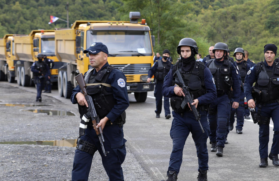 Kosovo police officers patrol by trucks where Kosovo Serbs block a road near the northern Kosovo border crossing of Jarinje, Monday, Sept. 20, 2021. Tensions soared Monday at the border between Kosovo and Serbia as Kosovo deployed additional police to implement a rule to remove Serbian license plates from cars entering Kosovo, while Serbs protested the move. (AP Photo/Bojan Slavkovic)