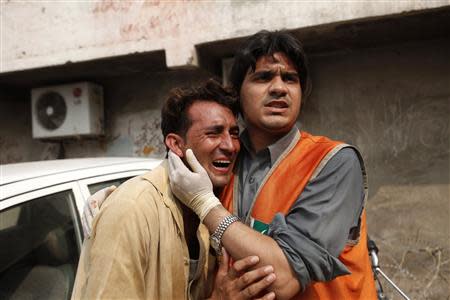 A rescue worker comforts a man as he cries over the death of his brother, who was killed in a bomb blast, at a hospital in Peshawar September 27, 2013. REUTERS Fayaz Aziz