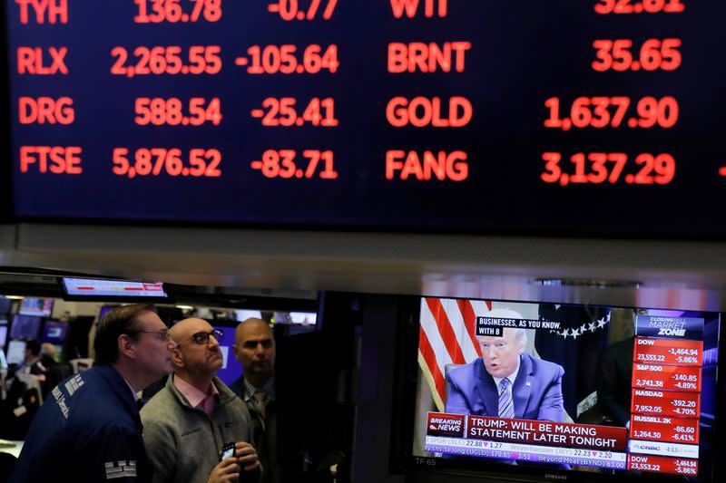 FILE PHOTO: U.S. President Donald Trump is seen on a screen under trading figures during his meeting with bank executives as traders work on the floor of the New York Stock Exchange (NYSE) in New York City