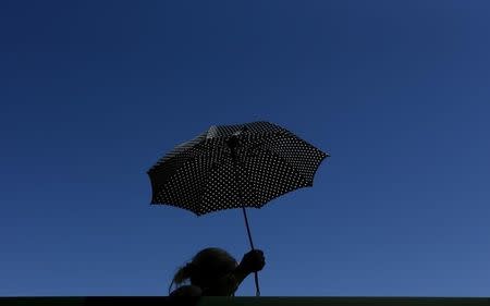 Spectator sheilds from the sun using an umbrella on Court 18 at the Wimbledon Tennis Championships in London, June 30, 2015. REUTERS/Suzanne Plunkett