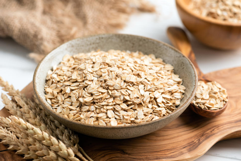 Rolled oats, oat flakes in bowl on wooden table.