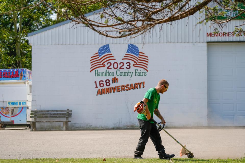 Adam Galliher weeds unruly grass around the lawns of the Hamilton County Fairgrounds on Friday, Aug. 4, 2023.