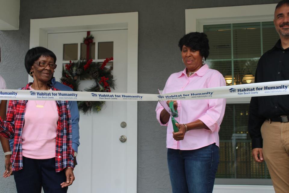 Gerlene Green (left), watches her daughter Consuela Green (right) cut the ribbon of their new home in Belle Glade.