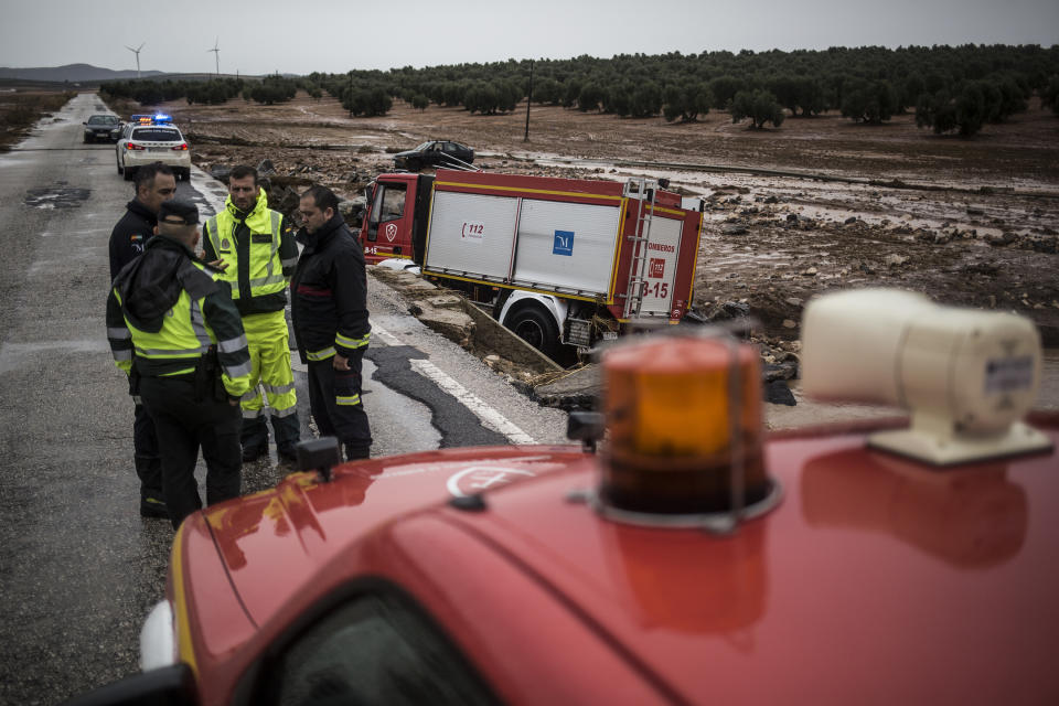 Spanish civil guards and firefighters stand near a crashed firefighting truck near the village of Campillos, Spain, where heavy rain and floods have caused severe damage and the death of a firefighter according to Spanish authorities, on Sunday, Oct. 21 2018. Emergency services for the southern region of Andalusia say that the firefighter went missing when his truck overturned on a flooded road during heavy rains that fell through the night, and his body was found after a search Sunday morning. (AP Photo/Javier Fergo)