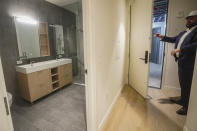 Malek Hajar, senior project manager at the Vanbarton Group, shows a bathroom inside a model apartment while touring a high rise undergoing conversion from commercial to residential apartments, Tuesday, April 11, 2023, in New York. A growing number of developers are considering converting empty office towers into housing as part of an effort to revive struggling downtown business districts that emptied out during the pandemic. (AP Photo/Bebeto Matthews)