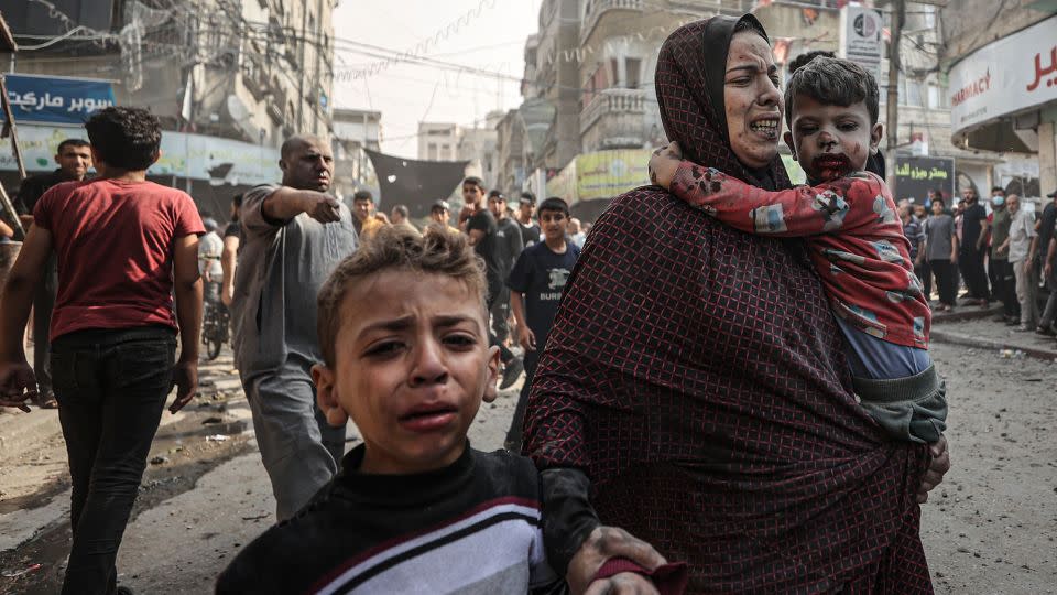 A woman and children, all injured, try to get to the safety amid destruction and chaos caused by Israeli airstrikes on Bureij refugee camp in Gaza on Thursday. - Mustafa Hassona/Anadolu/Getty Images