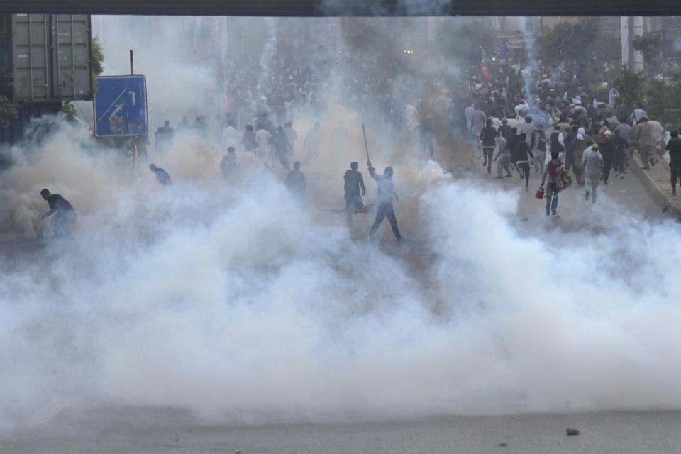 Supporters of former Pakistani Prime Minister Imran Khan's party, 'Pakistan Tehreek-e-Insaf' run for cover after police fire tear gas shell during a protest to condemn a shooting incident on their leader's convoy, in Rawalpindi, Pakistan, Friday, Nov. 4, 2022. Khan who narrowly escaped an assassination attempt on his life the previous day when a gunman fired multiple shots and wounded him in the leg during a protest rally is listed in stable condition after undergoing surgery at a hospital, a senior leader from his party said Friday. (AP Photo/Mohammad Ramiz)