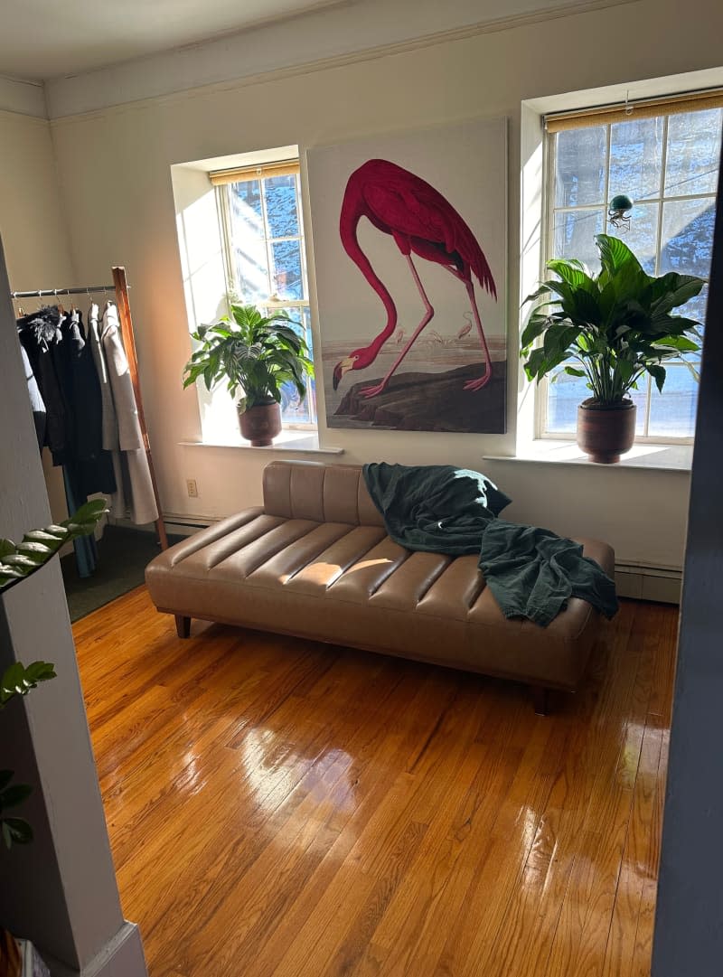 A large print of a flamingo above a leather brown lounge chair.
