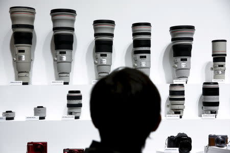 FILE PHOTO: A man looks at Canon lenses and cameras at the Canon stall during the CP+ camera and photo trade fair in Yokohama, Japan, February 25, 2016. REUTERS/Thomas Peter/File Photo