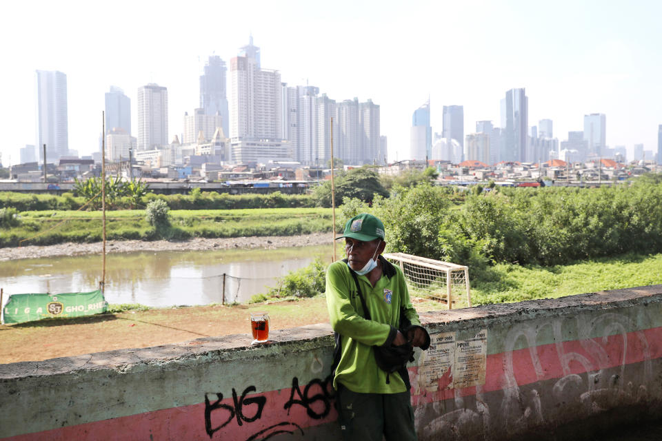 A municipal worker takes a break as the hazy city skyline is seen in the background in Jakarta, Indonesia, Thursday, Sept. 16, 2021. An Indonesian court ruled Thursday that President Joko Widodo and six other top officials have neglected to fulfill citizens' rights to clean air and ordered them to improve the poor air quality in the capital. (AP Photo/Tatan Syuflana)
