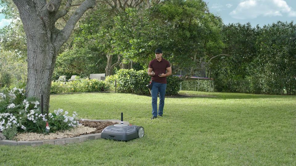 Man setting up an iRobot Terra robotic lawn mower