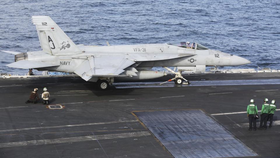 In this Monday, March 20, 2017 photograph, the pilot of an F-18 fighter jet salutes as he prepares to take off from the USS George H.W. Bush as it travels toward the Strait of Hormuz. The arrival of the nuclear-powered aircraft carrier to the Persian Gulf marks the first such deployment under new U.S. President Donald Trump. (AP Photo/Jon Gambrell)