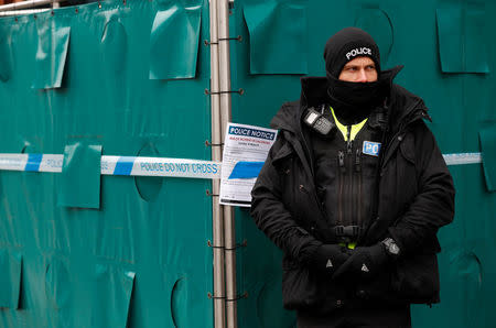 A police officer stands next to screening surrounding a restaurant which was visited by former Russian intelligence officer Sergei Skripal and his daughter Yulia before they were found on a park bench after being poisoned in Salisbury, Britain, March 19, 2018. REUTERS/Peter Nicholls