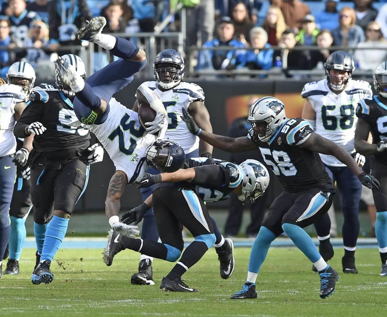 Seattle’s Chris Carson (32) is upended by Carolina’s Eric Reid (25) in the second half of Sunday’s game. Carson surprisingly landed on his feet. (AP)