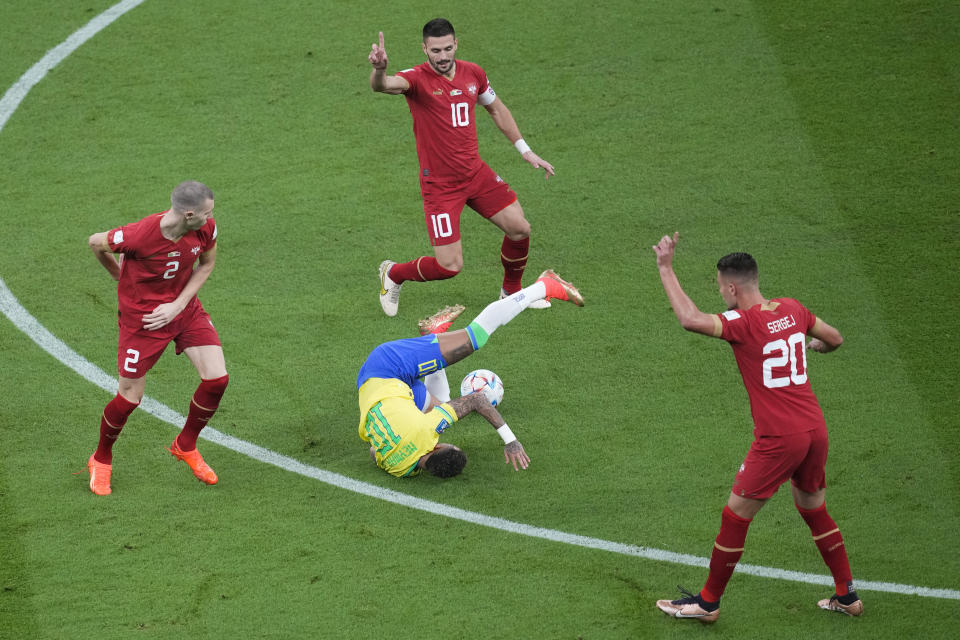 Brazil's Neymar centrer lies on the pitch after he was fouled by Serbia's Strahinja Pavlovic , left, during the World Cup group G soccer match between Brazil and Serbia, at the the Lusail Stadium in Lusail, Qatar on Thursday, Nov. 24, 2022. (AP Photo/Darko Vojinovic)