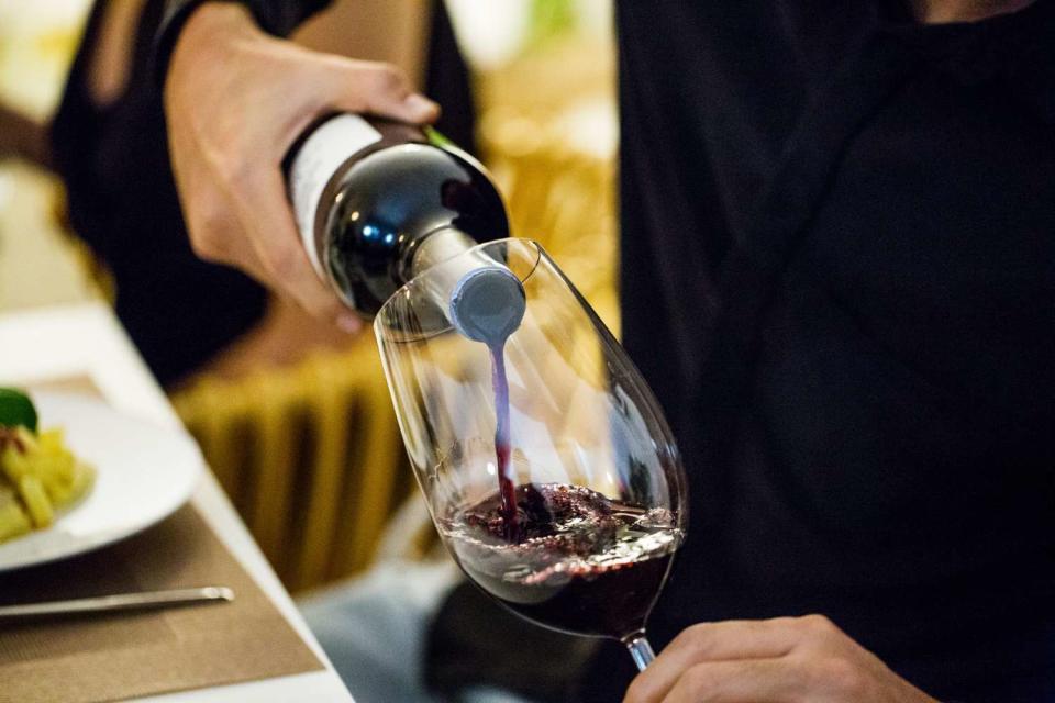 man pouring red wine in glass