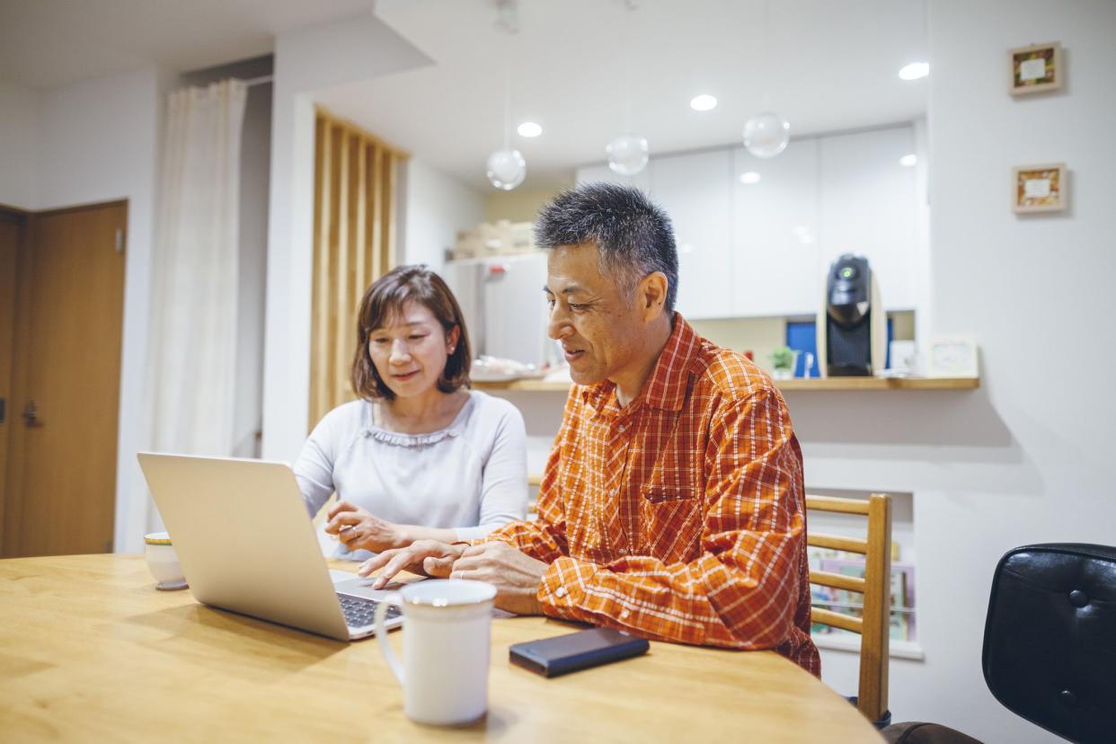 mature couple drafting document on laptop in home