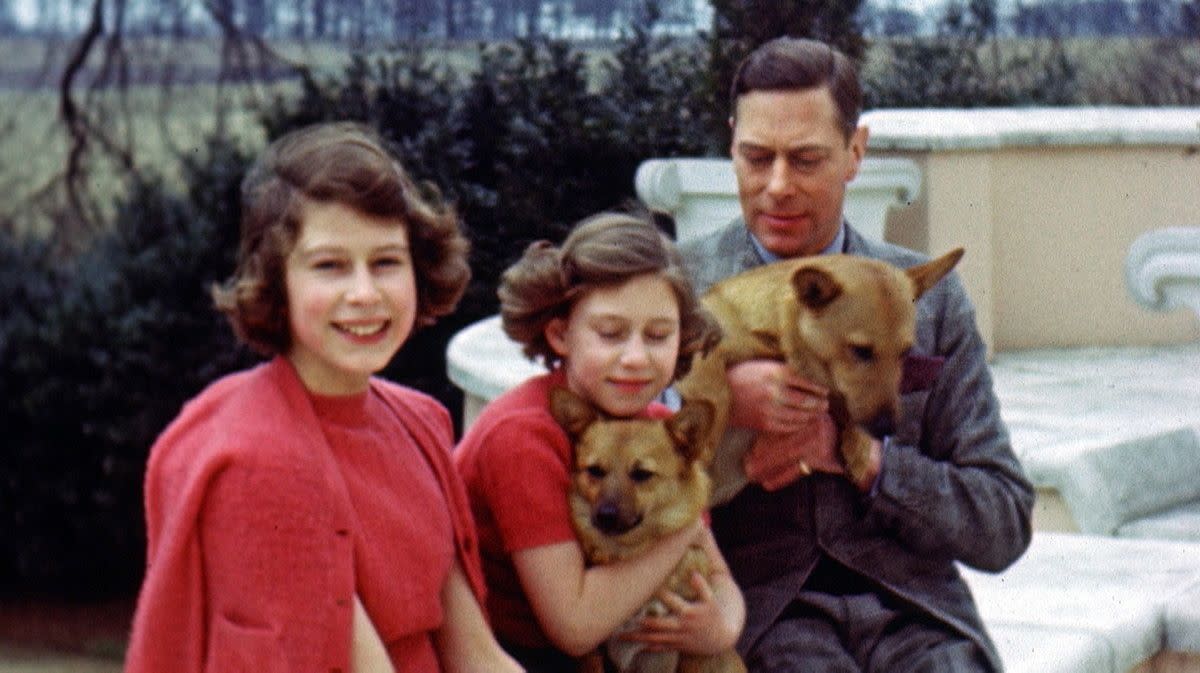 Princess Elizabeth, left, Princess Margaret and their father King George VI cuddle with two dogs on a bench in Britain.