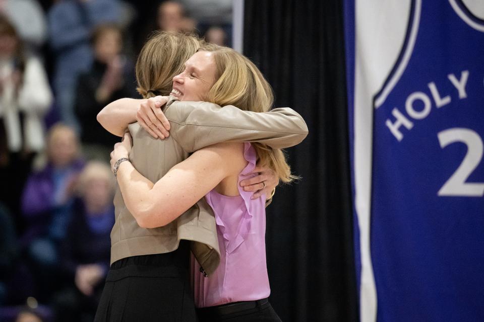 Kathleen Courtney, left, embraces Amy O'Brien Davagian during Saturday's ceremony retiring the numbers of former Holy Cross women's basketball players.