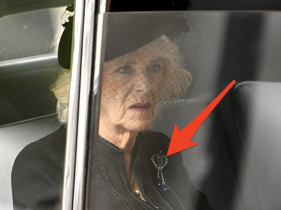 camilla riding in a car to the queen's funeral with an arrow pointing to her broach