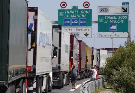 Truck drivers wait near their lorries blocked on a road which leads to the Channel Tunnel terminal in Coquelles near Calais, northern France, June 30, 2015. REUTERS/Vincent Kessler