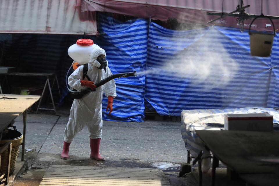 A worker sprays disinfectant as a precaution against the coronavirus at Klong Toey market in Bangkok, Thailand, Friday, Jan. 15, 2021. The market was temporarily closed after a person there tested positive for the coronavirus earlier this week. Thailand's government recently announced new measures, including partial lockdowns with strict travel restrictions in some areas, after a surge of coronavirus cases. Schools, bars, gambling parlors and other public gathering places were closed. (AP Photo/Sakchai Lalit)