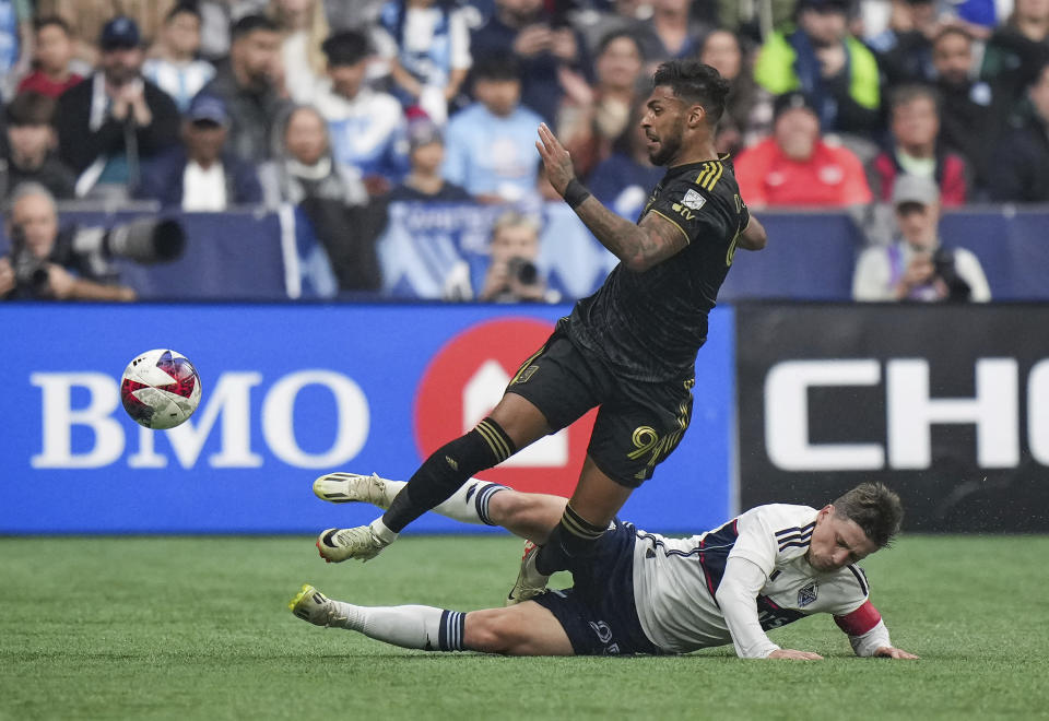 Los Angeles FC's Denis Bouanga (99) is upended by Vancouver Whitecaps' Ryan Gauld, bottom, who slides to take the ball away from him during the second half in Game 2 of a first-round MLS playoff soccer match in Vancouver, British Columbia, Sunday, Nov. 5, 2023. (Darryl Dyck/The Canadian Press via AP)