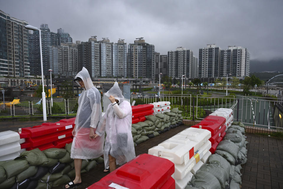 People in rain coats walk past sandbagged barricades setup for Typhoon Saola as it passes through Lei Yue Mun district in Hong Kong, on Saturday, Sept. 2, 2023. Typhoon Saola made landfall in southern China before dawn Saturday after nearly 900,000 people were moved to safety and most of Hong Kong and other parts of coastal southern China suspended business, transport and classes. (AP Photo/Billy H.C. Kwok)
