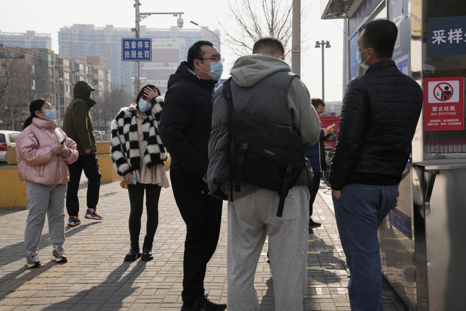 Workers and residents stand near a nuclei test station in Beijing, China, Tuesday, Jan. 18, 2022. The first reported case of the omicron variant has prompted stepped-up measures in Beijing, just weeks before it hosts the Winter Olympic Games. (AP Photo/Ng Han Guan)