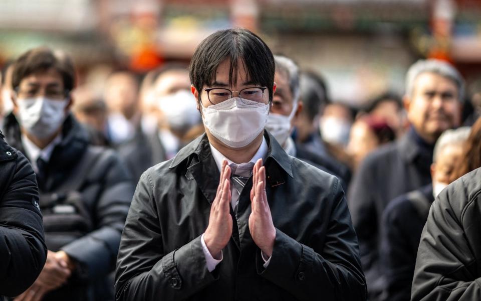 The mood was sombre as people made their traditional prayers on the first business day of the year after the deadly earthquake and collision of two planes at Tokyo's main airport