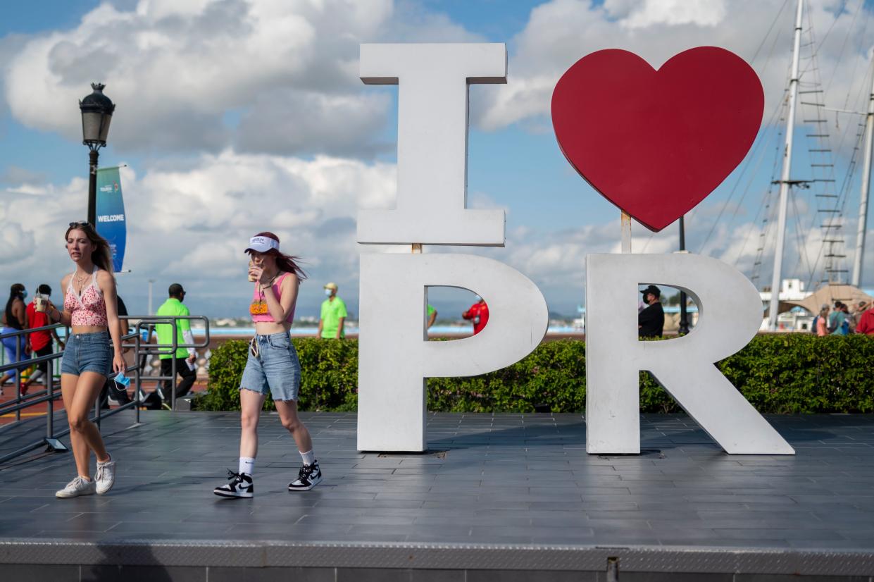 Tourists walk through the docking area after exiting Carnival's Mardi Gras cruise ship in the bay of San Juan, Puerto Rico, Aug. 3, 2021.