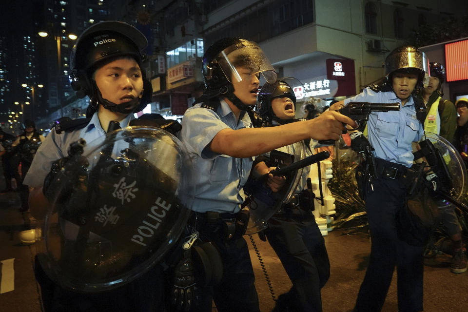 Policemen pull out their guns after a confrontation with demonstrators during a protest in Hong Kong, Sunday, Aug. 25, 2019. Hong Kong police have rolled out water cannon trucks for the first time in this summer's pro-democracy protests. The two trucks moved forward with riot officers Sunday evening as they pushed protesters back along a street in the outlying Tsuen Wan district. (AP Photo/Vincent Yu)