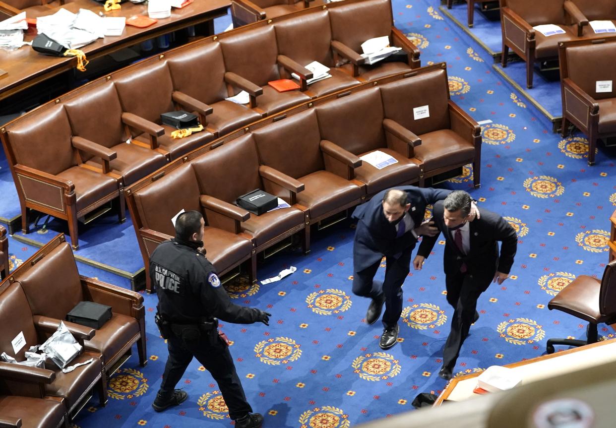 Members of congress run for cover as protesters try to enter the House Chamber during a joint session of Congress on January 06, 2021, in Washington, DC.