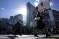 People wearing protective masks to help curb the spread of the coronavirus walk along a pedestrian crossing Friday, Jan. 21, 2022, in Tokyo. Restaurants and bars will close early in Tokyo and a dozen other areas across Japan beginning Friday as the country widens COVID-19 restrictions due to the omicron variant causing cases to surge to new highs in metropolitan areas. (AP Photo/Eugene Hoshiko)