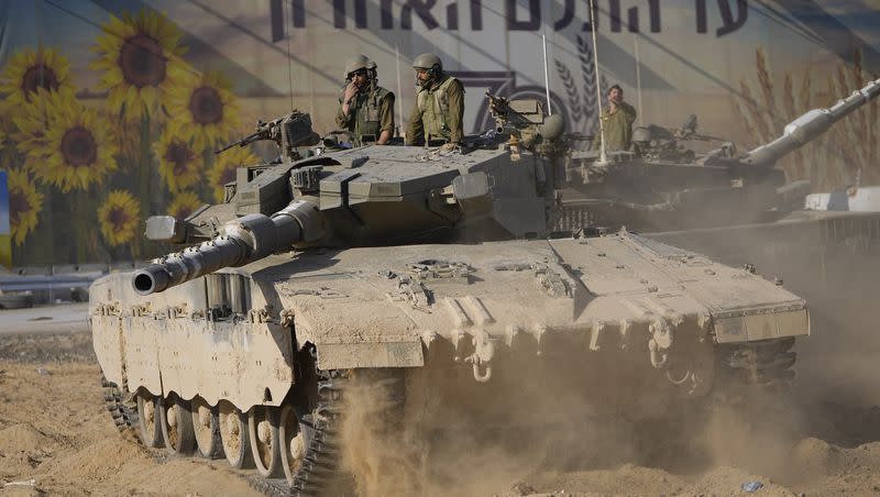 Israeli soldiers move a tank at a staging area near the border with Gaza Strip, in southern Israel on Sunday, Oct. 15, 2023.