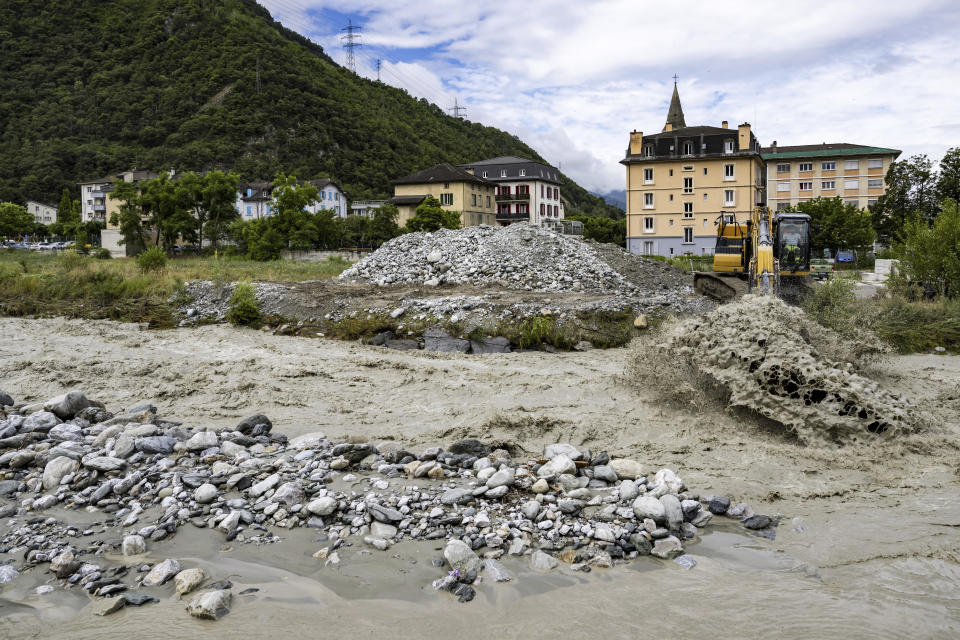 An excavator removes stones from the bed of the Navizence river, which flows into the Rhone, in Chippis, canton Valais, Switzerland, Saturday June 22, 2024. (Jean-Christophe Bott/Keystone via AP)