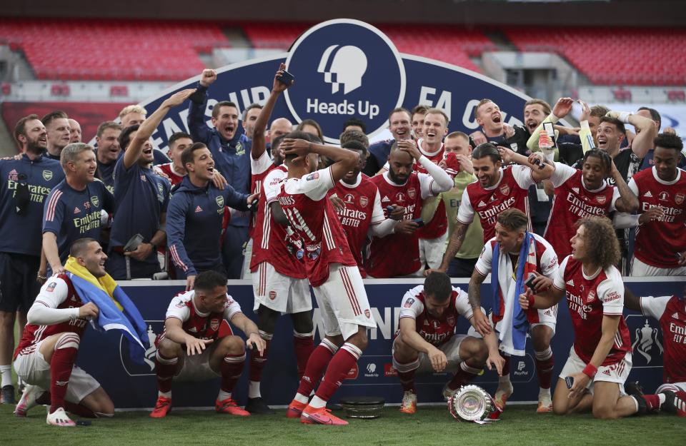 Pierre-Emerick Aubameyang, al centro, deja caer el trofeo durante los festejos del Arsenal tras ganar la Copa FA al vencer 2-1 al Chelsea el sábado 1 de agosto de 2020, en el estadio Wembley, de Londres. (Adam Davy/Pool via AP)