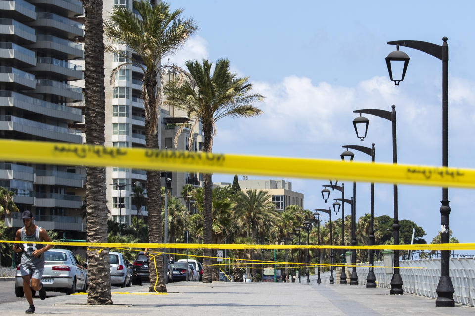 A man jogs near a cordoned off area which is almost empty of residents and tourists, officially closed following the government's measures to help stop the spread of the coronavirus, in Beirut, Lebanon, Monday, Aug. 3, 2020. (AP Photo/Hassan Ammar)