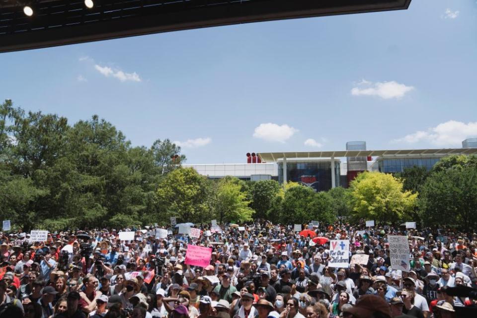 crowd holds up signs