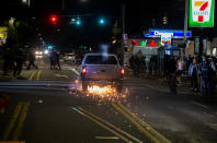 A driver in a pickup truck accelerates towards the crowd, hitting and dragging a motorcycle during a protest in Portland, Ore., on Tuesday, Aug. 4, 2020. A riot was declared early Wednesday during demonstrations in Portland after authorities said people set fires and barricaded public roadways.(Dave Killen /The Oregonian via AP)