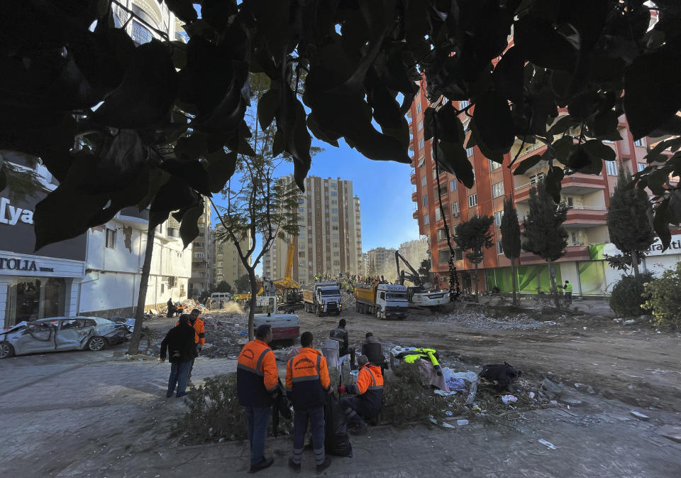 People watch as rescuers search in a destroyed building in Adana, southeastern Turkey, Thursday, Feb. 9, 2023. Tens of thousands of people who lost their homes in a catastrophic earthquake huddled around campfires in the bitter cold and clamoured for food and water Thursday, three days after the temblor hit Turkey and Syria.(AP Photo/Lefteris Pitarakis)