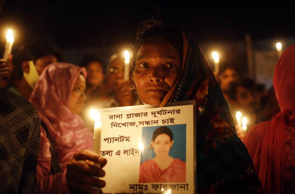 A Bangladeshi woman holds a candle with a portrait of a missing relative, victim of last year’s Rana Plaza building collapse, during a gathering to pay tributes on the eve of the tragedy in Savar, near Dhaka, Bangladesh, Wednesday, April 23, 2014. More than 1,100 people were killed when the illegally constructed, 8-storey building collapsed on April 24, 2013, in a heap along with thousands of workers in the five garment factories in the building. Placard reads “Farzana, Rana Plaza missing.” (AP Photo/A.M. Ahad)