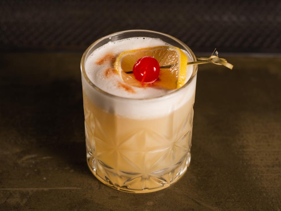 Amaretto sour in glass with orange and cherry garnish