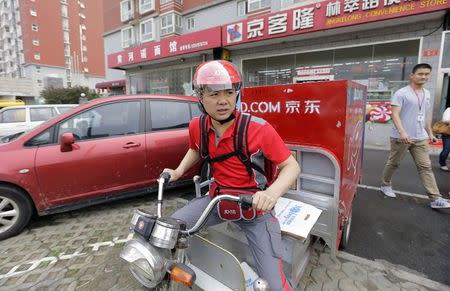 Richard Liu, CEO and founder of China's e-commerce company JD.com, rides an electric tricycle as he leaves a delivery station to deliver goods for customers to celebrate the anniversary of the founding of the company, in Beijing, June 16, 2014. REUTERS/Jason Lee