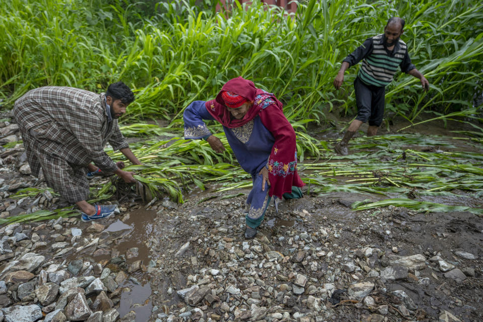 FILE - A Kashmiri woman pulls herself out of the mud as her relatives inspect damage made to crops after a cloudburst on the outskirts of Srinagar, Indian controlled Kashmir, July 22, 2023. Such intense rainfall events, especially when more than 10 centimeters (3.94 inches) of rainfall occurs within a 10 square kilometers (3.86 square miles) region within an hour are called cloudbursts and have potential to wreak havoc, causing intense flooding and landslides that affect thousands in mountain regions. (AP Photo/Dar Yasin, File)
