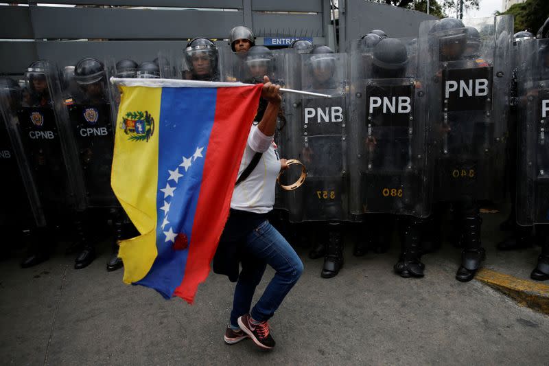 A woman waves a Venezuelan flag in front of security forces during a demonstration in Caracas