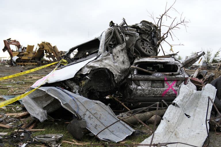 Autos dañados apilados junto a una carretera tras un tornado en Iowa.