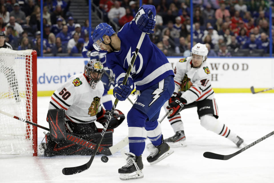 Tampa Bay Lightning defenseman Kevin Shattenkirk (22) tries to control the puck in front of Chicago Blackhawks goaltender Corey Crawford (50) and defenseman Lucas Carlsson (46) during the second period of an NHL hockey game Thursday, Feb. 27, 2020, in Tampa, Fla. (AP Photo/Chris O'Meara)