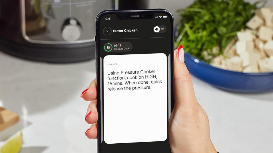 A hand holding a phone displaying the app for the Instant Pot Pro Plus Smart Multi-Cooker