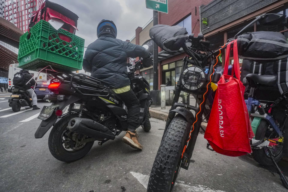 A food delivery worker rides off after a pickup from a fast-food restaurant on Brooklyn's Flatbush Avenue, Monday, Jan. 29, 2024, in New York. A wage law in New York City meant to protect food delivery workers is getting backlash from app companies like Uber, GrubHub and DoorDash, who have cut worker hours and made it more difficult to tip. (AP Photo/Bebeto Matthews)